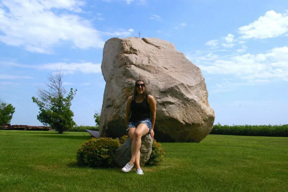 Woman sitting on small rock in front of Slayton Rock in Slayton, Iowa