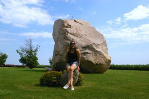 Woman sitting in front of giant boulder known as Slayton Rock near Casey, Iowa