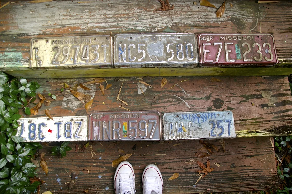 Feet on steps covered in old license plates at the Abita Mystery House in Abita Springs, Louisiana