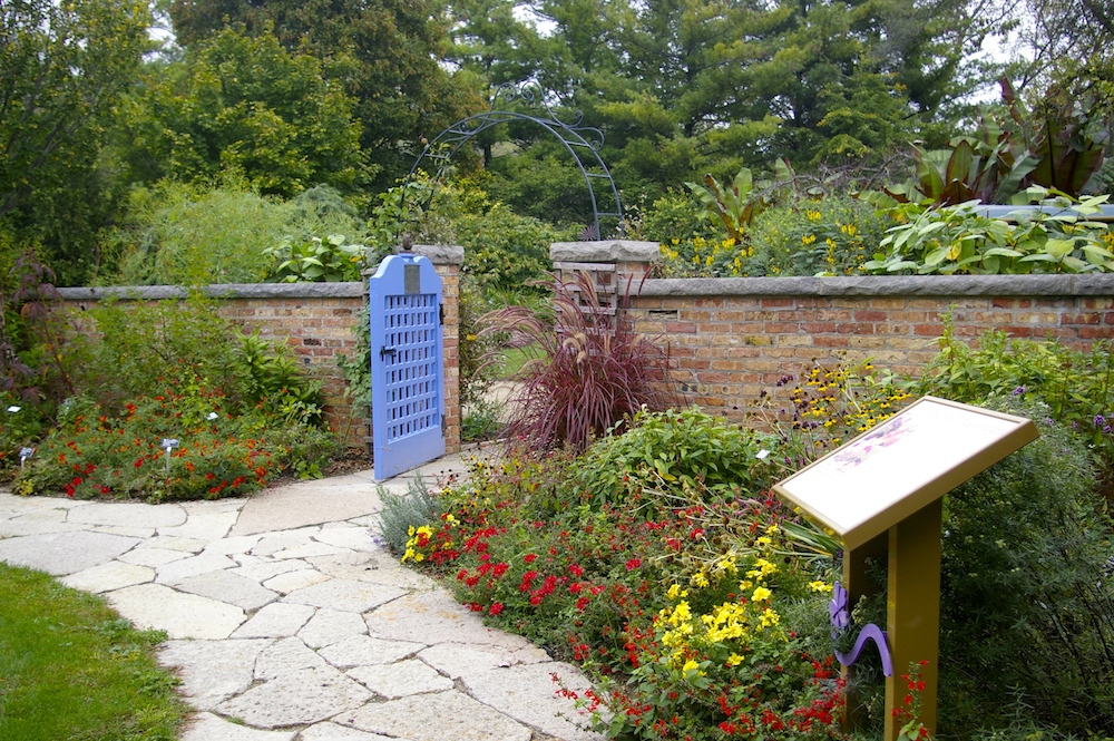 Wildflowers along a stone path leading to a wall with a blue door at the Rotary Botanical Gardens in Janesville, Wisconsin