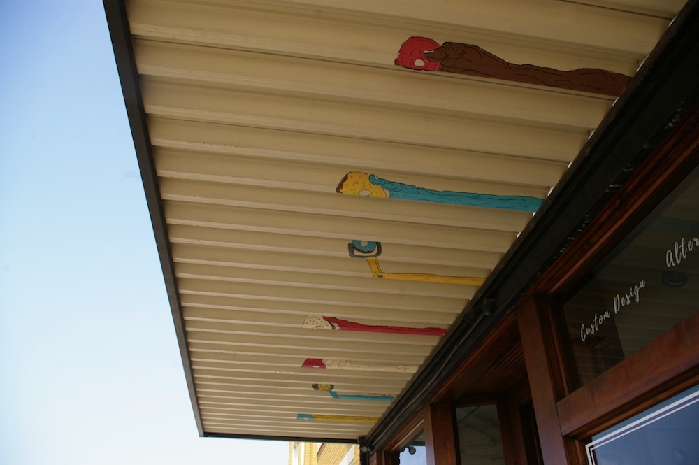 Mural on overhang of arms reaching for donuts at the Donut Whole in the Douglas Design District of Wichita, Kansas