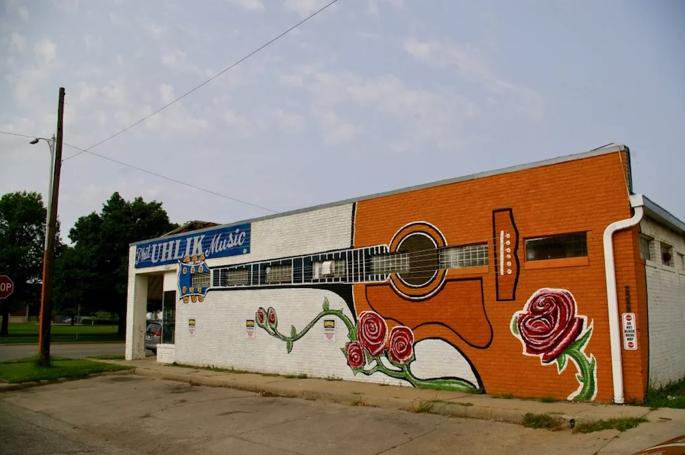 Giant orange guitar with roses painted on the side of a building in the Douglas Design District of Wichita, Kansas.