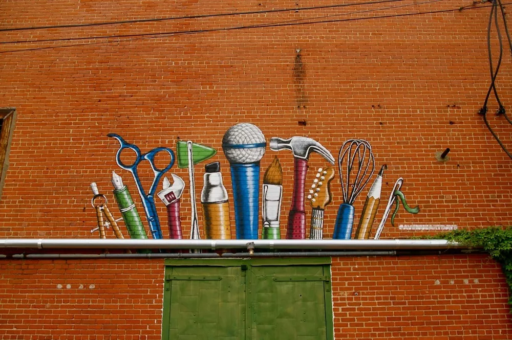 Art supplies painted on a brick wall above green doors in the Douglas Design District of Wichita, Kansas