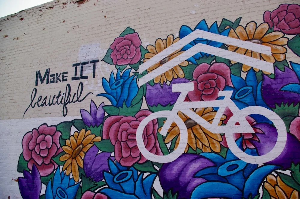 Colorful floral mural with a bicycle that says "Make it beautiful" in the Douglas Design District of Wichita, Kansas