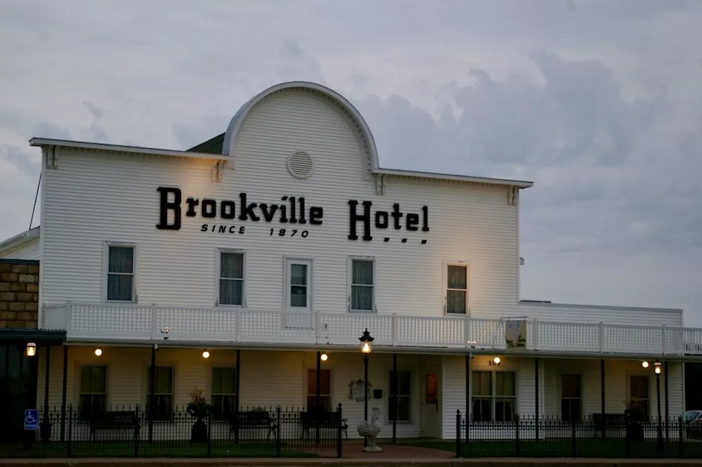 White facade with curved roof and wraparound porch of the Brookville Hotel in Abilene, Kansas