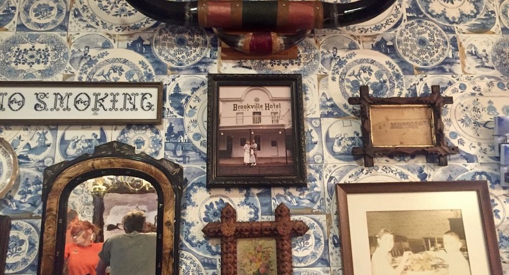 Longhorns and various artifacts mounted on a wall with blue and white floral wallpaper at the Brookville Hotel in Abilene, Kansas