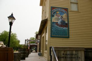 Yellow building with vintage poster and historic boardwalk in the Old Cowtown Museum in Wichita, Kansas