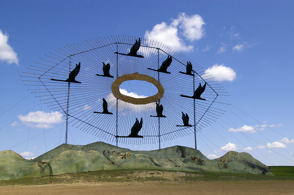 Large scrap metal sculpture featuring flapping geese in front of a golden metal sun called Geese in Flight, the World's Largest Scrap Metal Sculpture, located along the Enchanted Highway near Regent, North Dakota