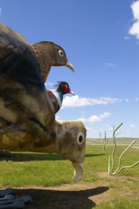 Large metal pheasant sculpture with red and green head along the Enchanted Highway near Regent, North Dakota