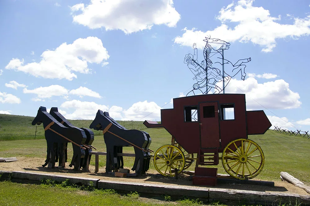 Metal sculpture of Teddy Roosevelt riding a horse behind a horse-drawn carriage along the Enchanted Highway near Regent, North Dakota
