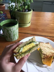 Coffee mug beside breakfast sandwich with pesto, egg and cheese at Thistle's Summit in Mount Vernon, Iowa