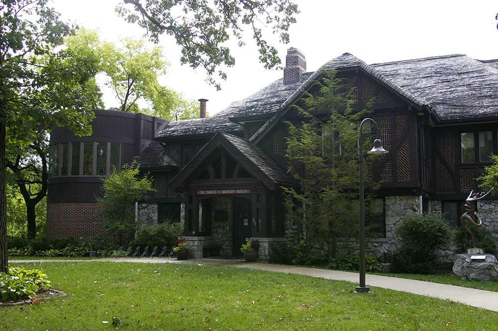 Exterior of brown lodge style building with slopping roof that serves as the Charles H. MacNider Art Center in Mason City, Iowa