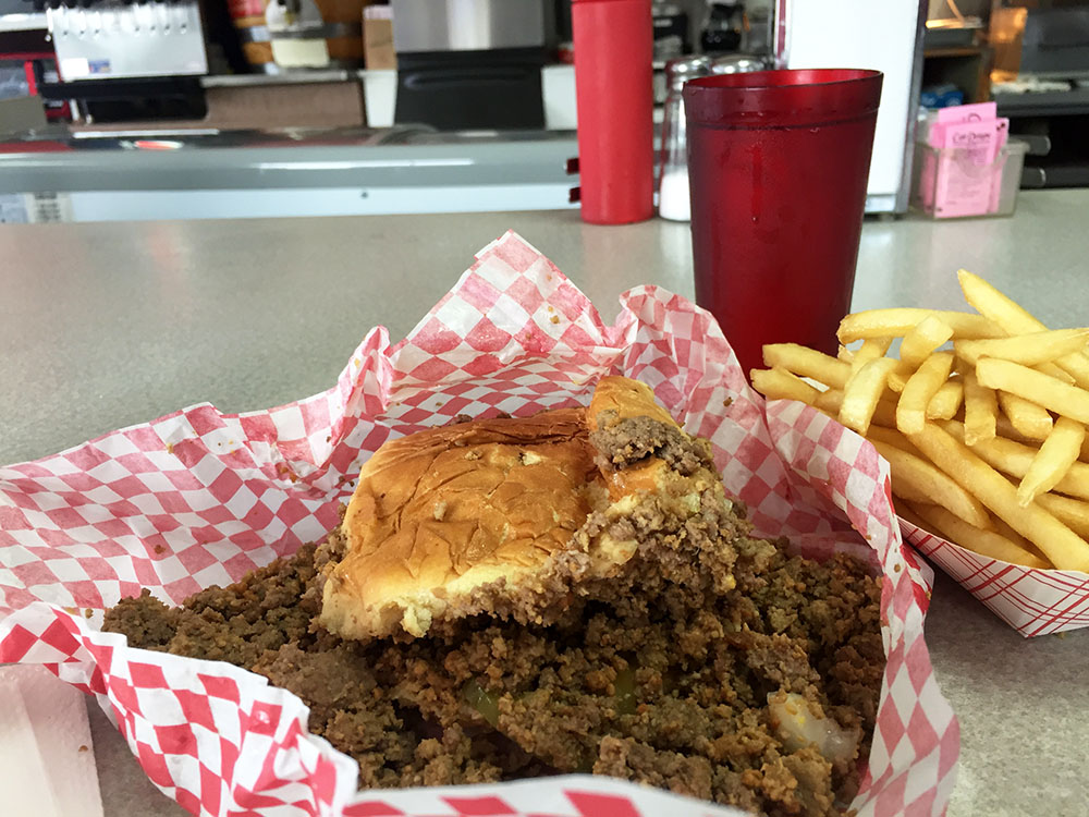Loose meat sandwich on a white and red checkered wrapper with a side of French fries at Pro's Sandwich Shop in Mason City, Iowa