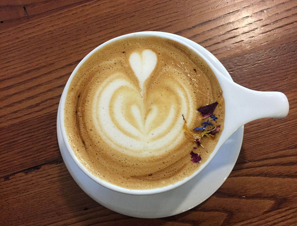 Latte in white mug with dried flowers at Horizon Line Coffee in Des Moines, Iowa