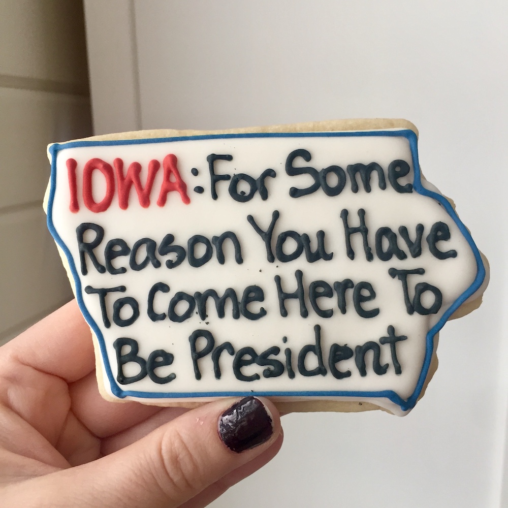 Sugar cookie with white frosting and text reading "IOWA: For some reason you have to come here to be president" made by One Sweet Kitchen