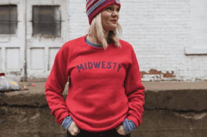 Blonde woman wearing red crewneck sweatshirt that says Midwesty