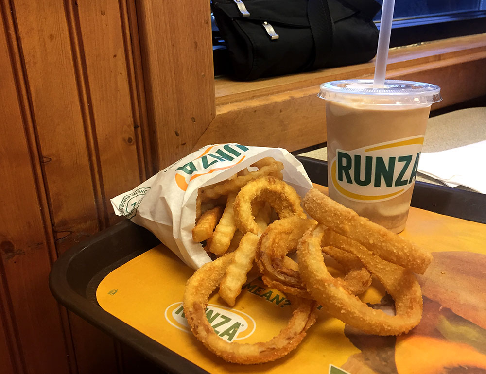 Bag of Runza onion rings and French fries next to a chocolate shake