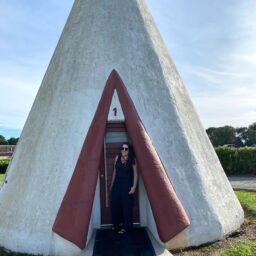 Woman standing in doorway of a giant concrete teepee at the Wigwam Village Inn #2 in Cave City, Kentucky