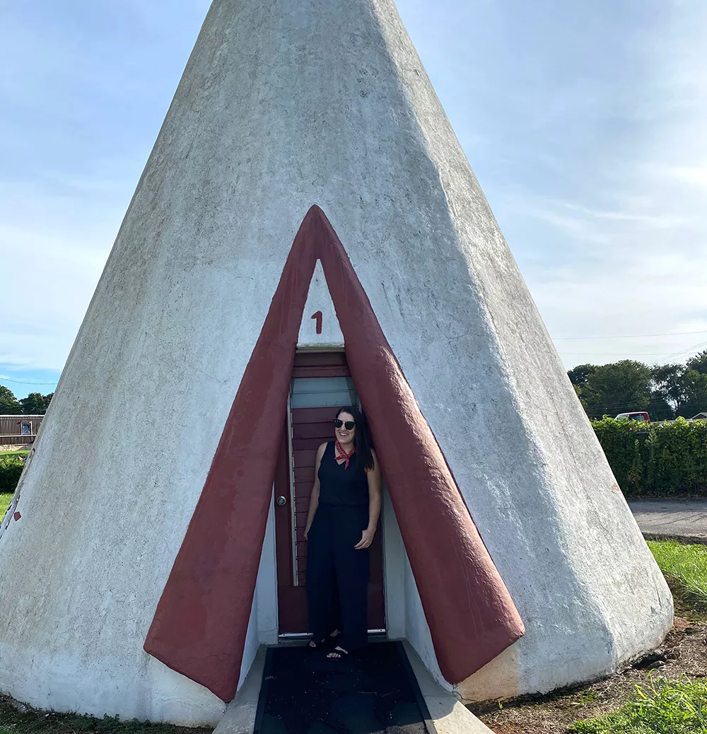 Woman standing in doorway of a giant concrete teepee at the Wigwam Village Inn #2 in Cave City, Kentucky