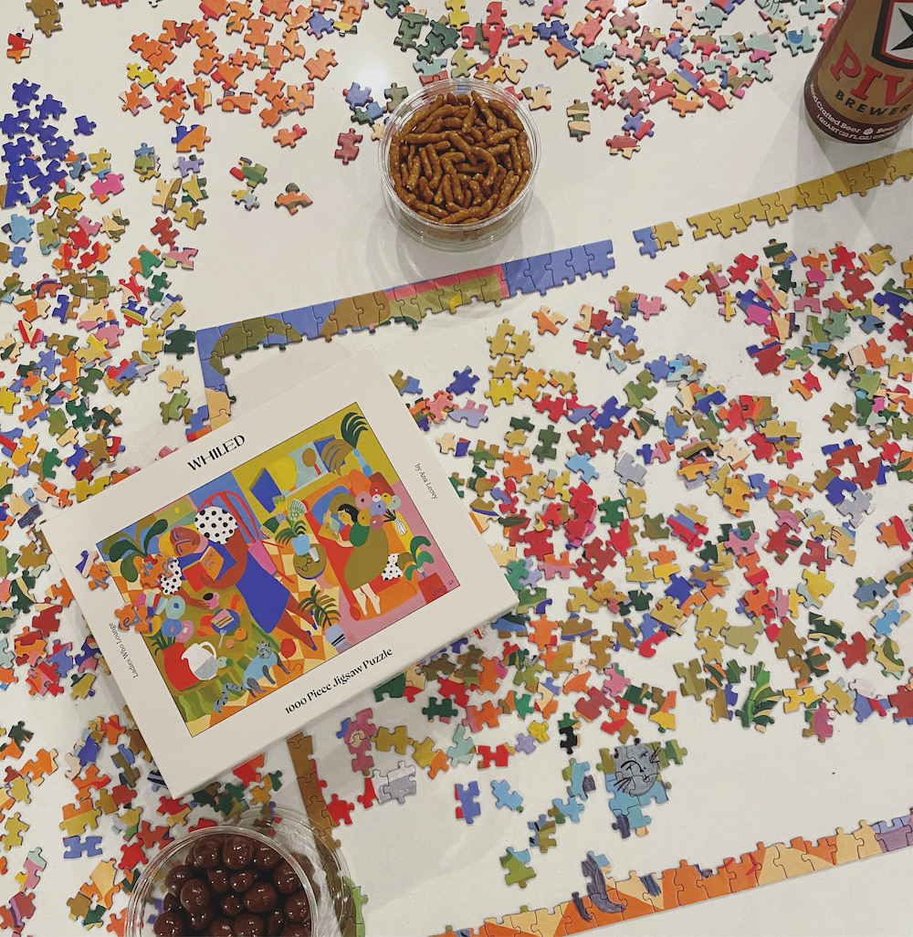 Whiled Ladies Who Lounge puzzle in-progress surrounded by snacks