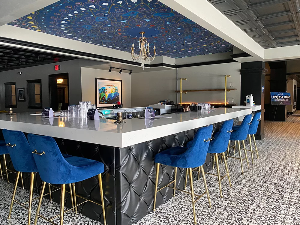 Bar with painted mural ceiling and blue velvet chairs at The Highlander Hotel in Iowa City, Iowa