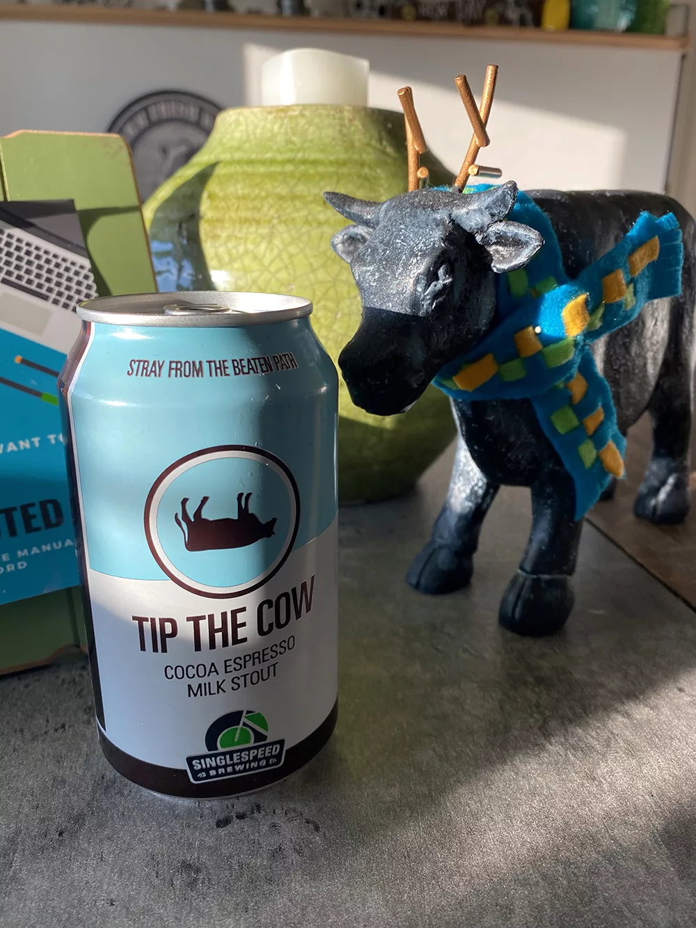 Can of Tip the Cow from Single Speed Brewing next to cow statue at New Day Dairy Guest Barn in Clarksville, Iowa