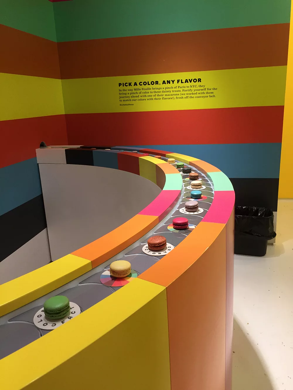 Rainbow macaroon conveyor belt installation at the Color Factory in New York City, New York