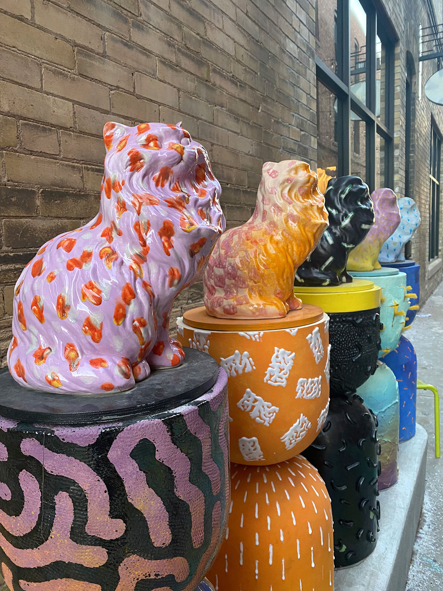 Public art piece featuring statues of colorful melting cats