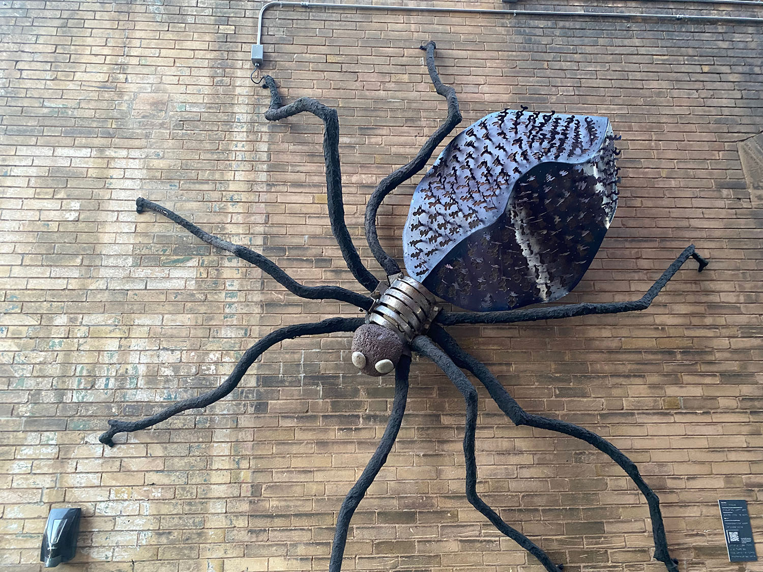 Giant spider sculpture attached to brick wall in Wichita, Kansas