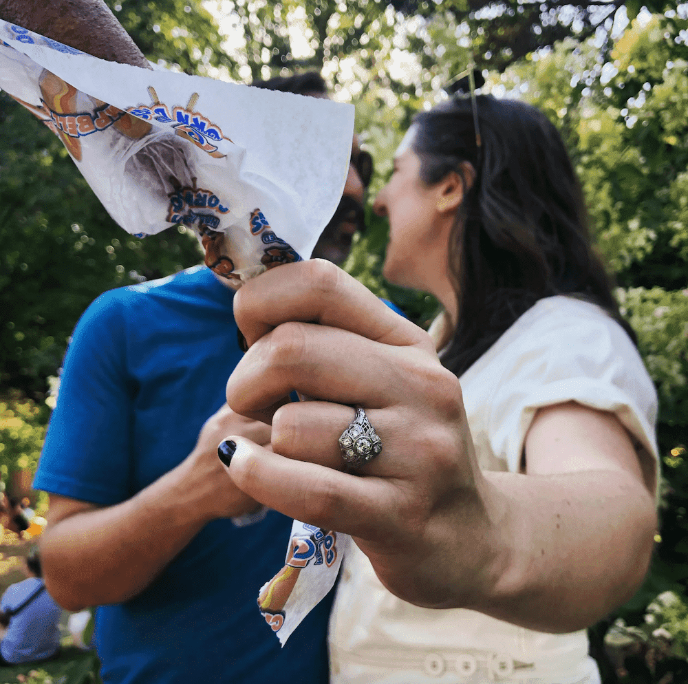 People kissing in background while one holds a corn dog