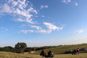 People watching hot air balloons in the sky over Indianola, Iowa during the National Balloon Classic