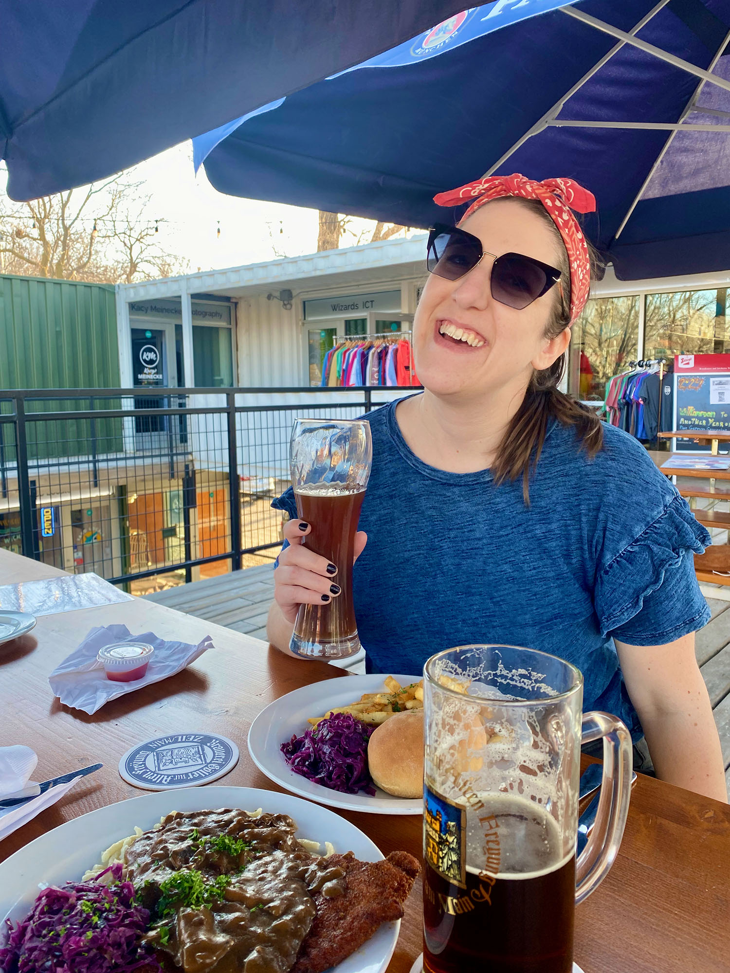 Woman holding beer with plate of food in front of her at Prost in Wichita, Kansas