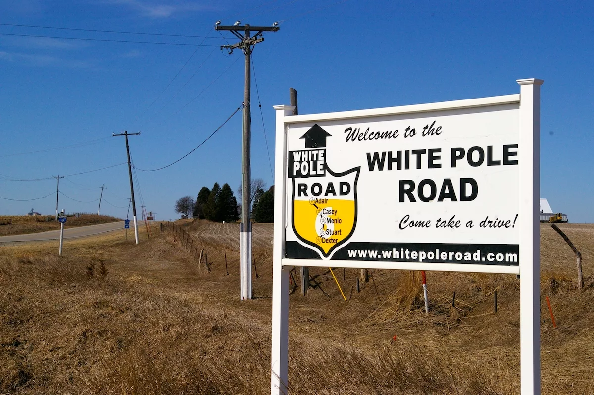 Sign for White Pole Road with painted telephone poles in the background