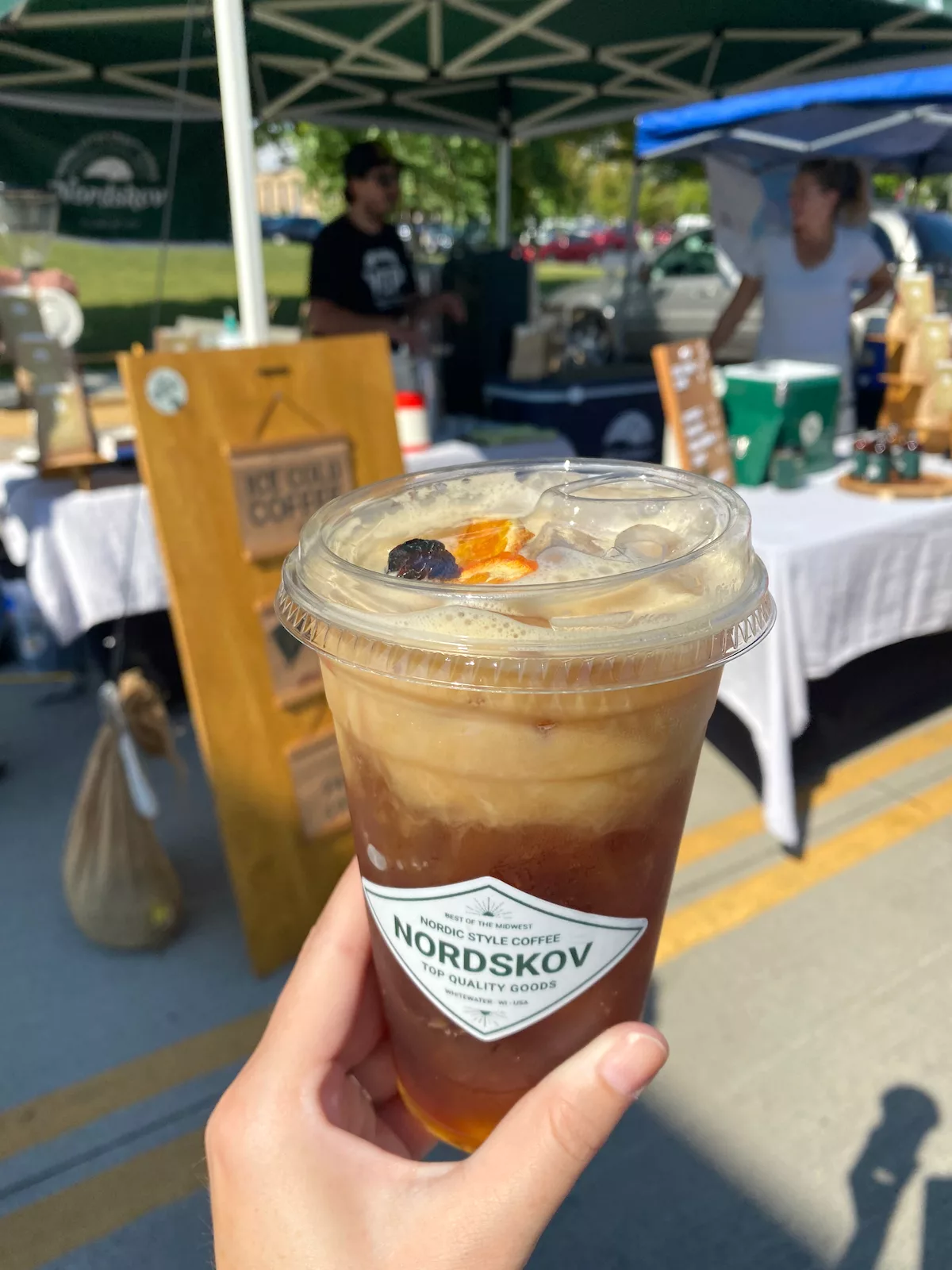 Hand holding iced coffee at Janesville Farmers Market in Janesville, Wisconsin