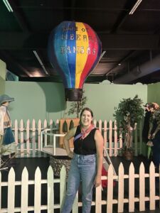 Woman posing in front of hot air balloon model that says "Spirit of Liberal, Kansas" at Dorothy's House & Land of Oz in Liberal, Kansas