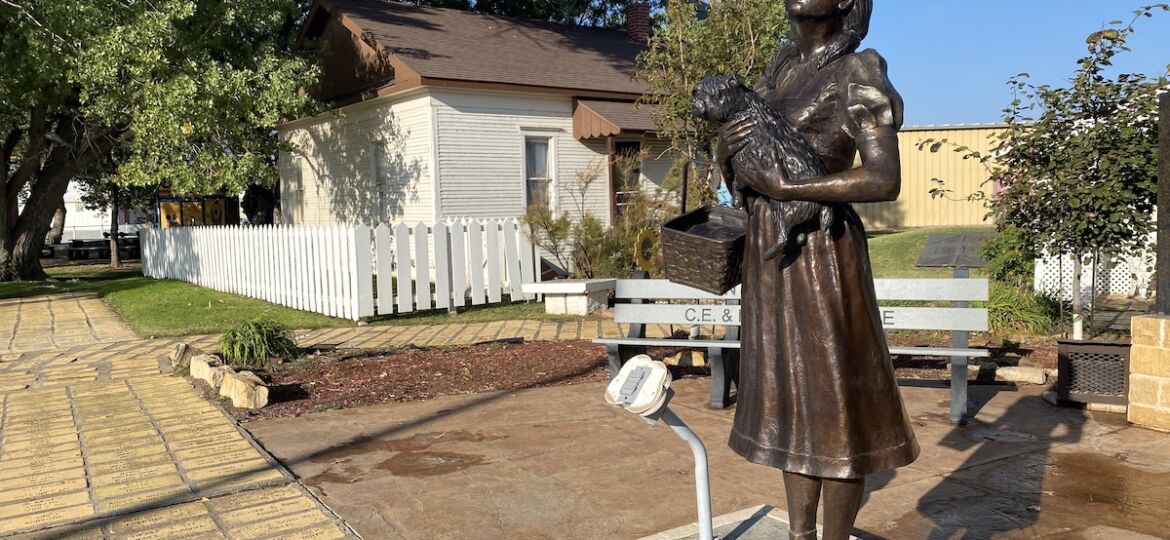 Bronze statue of Dorothy Gale holding Toto outside of Dorothy's House & Land of Oz in Liberal, Kansas
