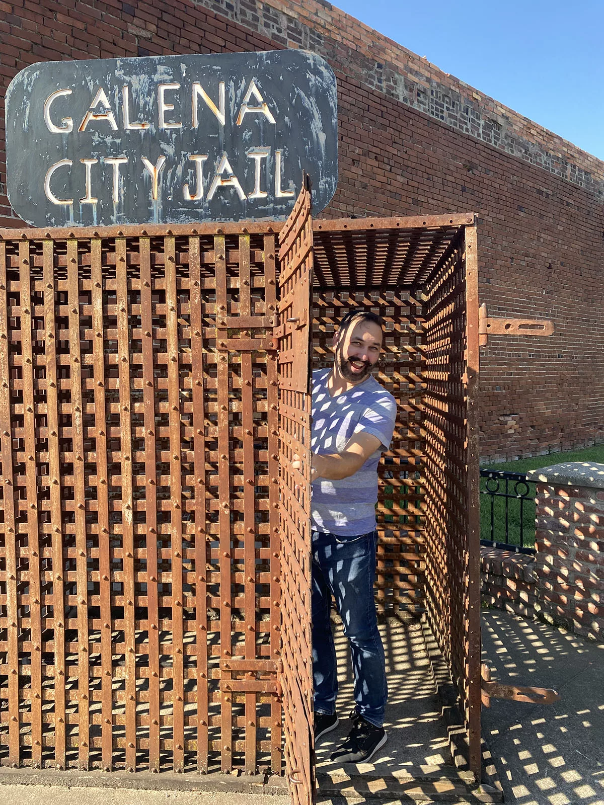 Man standing inside historic jail with sign that reads Galena City Jail in Galena, Kansas