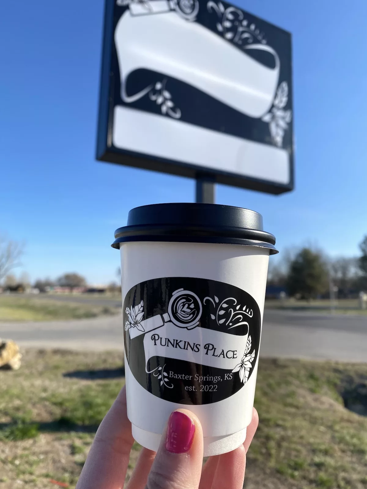 Hand holding coffee outside of Punkin's Place in Baxter Springs, Kansas
