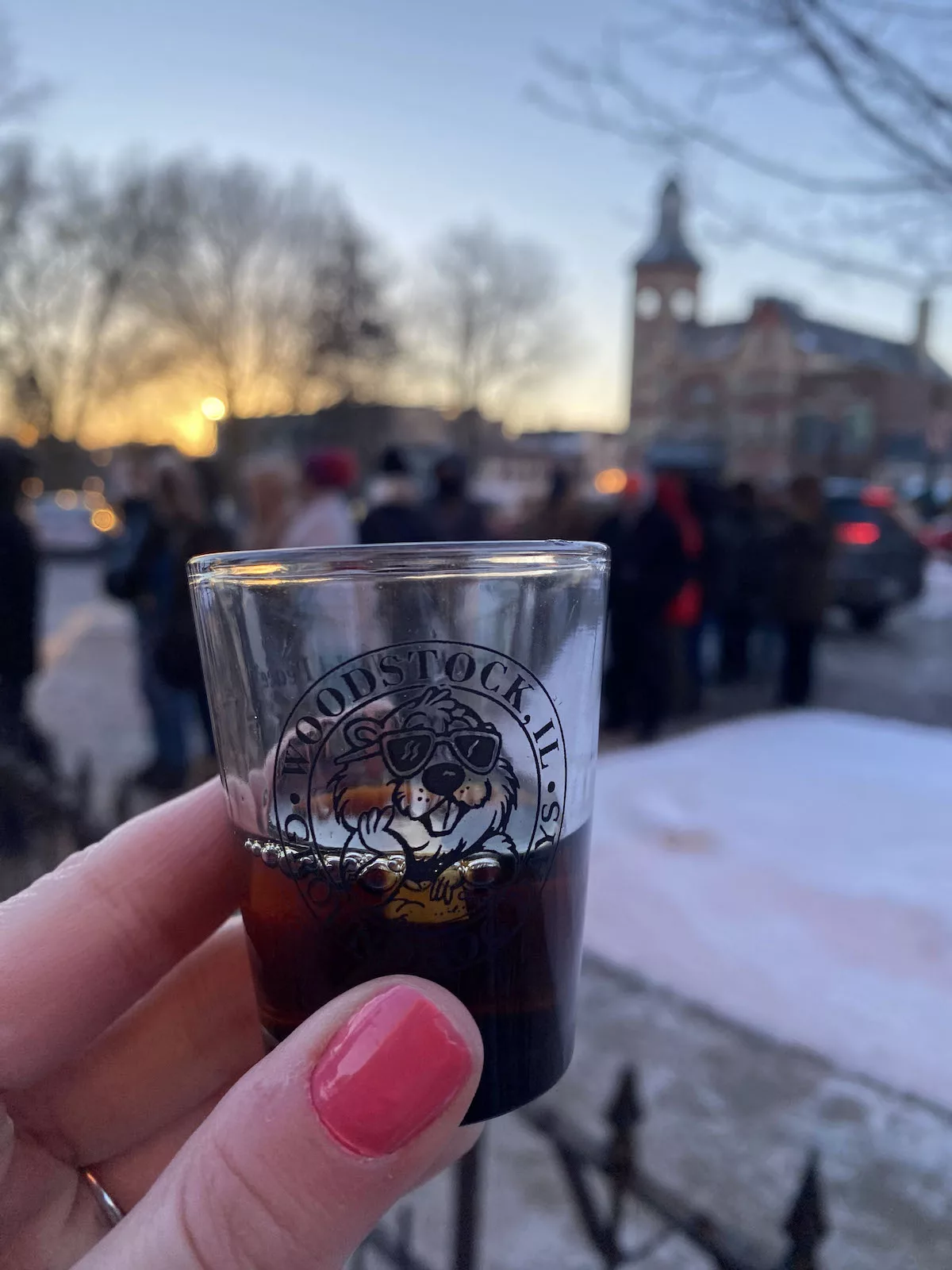 Hand holding a Groundhog Day shot glass for the Drink to World Peace on Groundhog Day in Woodstock, Illinois