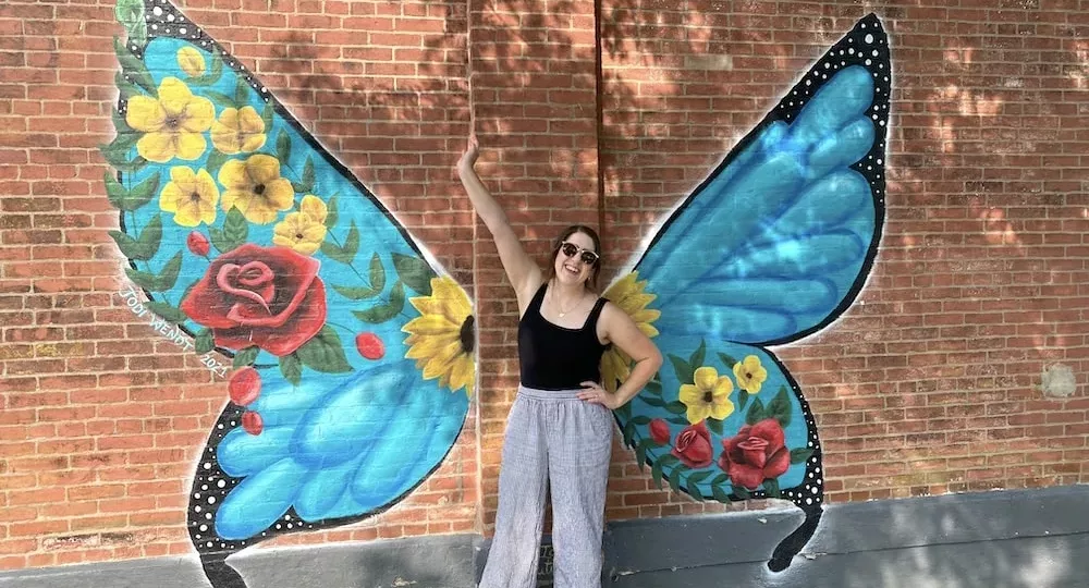 Woman standing in front of butterfly wing mural in Audubon, Iowa