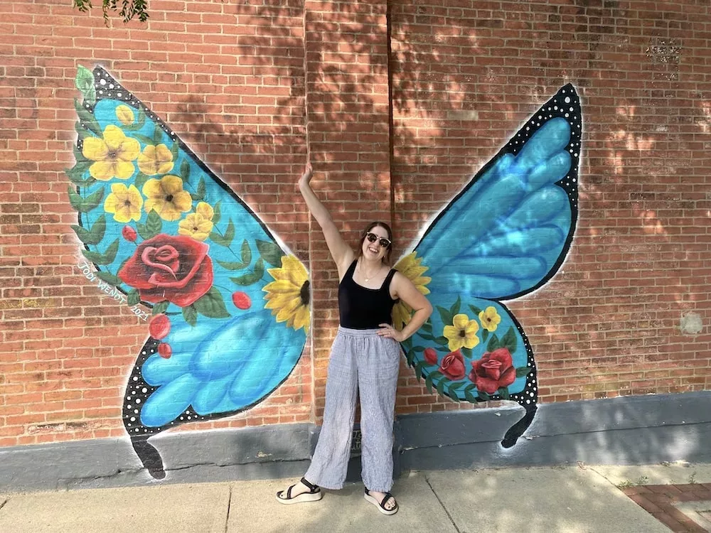 Woman standing in front of butterfly wing mural in Audubon, Iowa