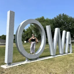 Woman standing in O of giant IOWA sign in Manning, Iowa
