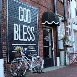 God Bless Clarksville mural with white bike in front of it in downtown Clarksville, Tennessee
